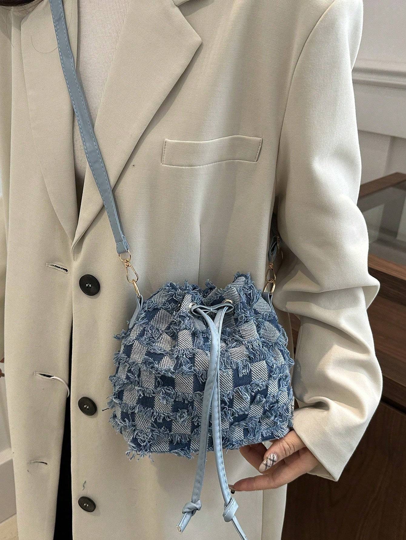 Person holding a blue textured handbag with a light-colored coat